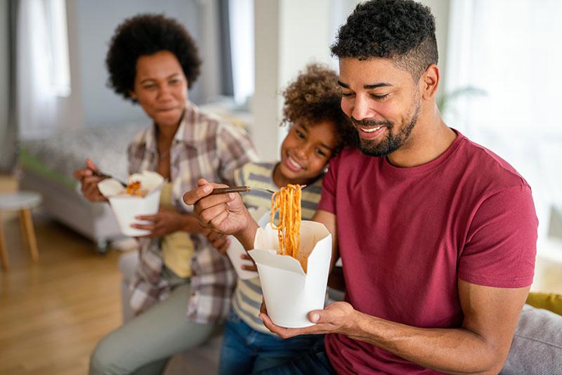 Happy-family-eating-at-living-room.-Home-delivary-takeaway-food
